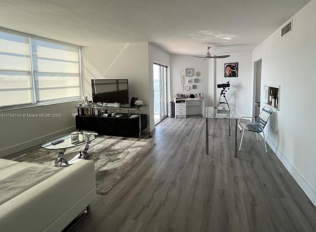 living area featuring baseboards, visible vents, ceiling fan, and wood finished floors