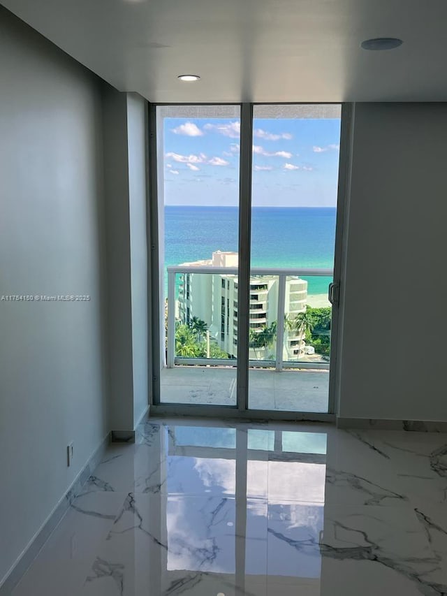 spare room with marble finish floor, a water view, and baseboards