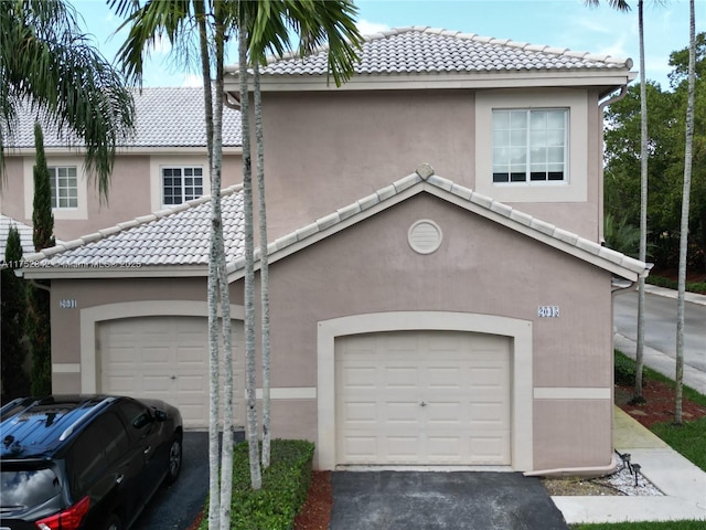 view of front facade featuring a tile roof, aphalt driveway, and stucco siding