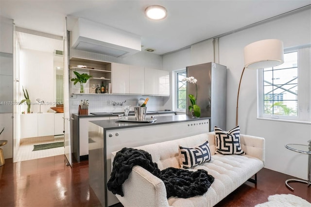 kitchen featuring a kitchen island, white cabinets, backsplash, open shelves, and dark countertops