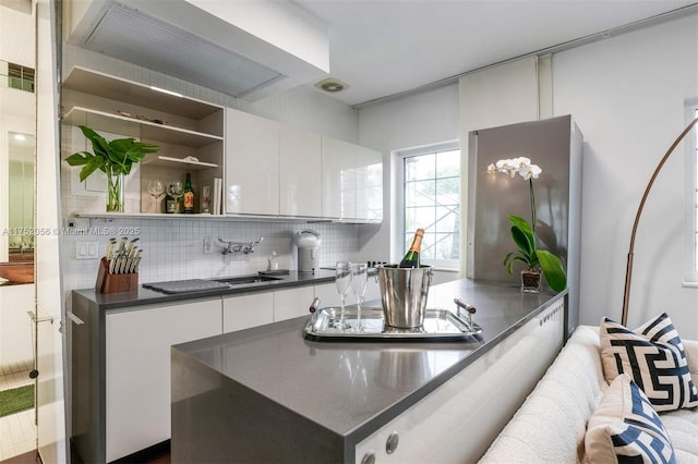 kitchen with premium range hood, white cabinetry, decorative backsplash, open shelves, and dark countertops