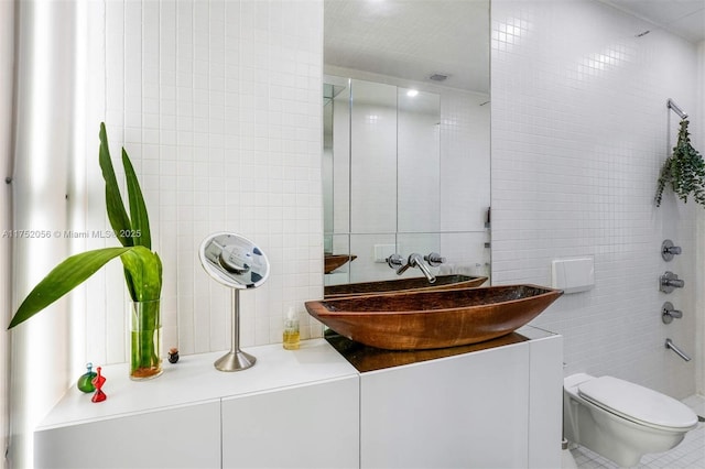 bathroom featuring toilet, walk in shower, vanity, and tile walls