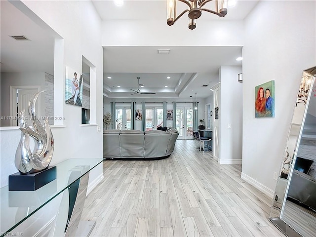 living area with ceiling fan, light wood-style flooring, recessed lighting, baseboards, and a raised ceiling