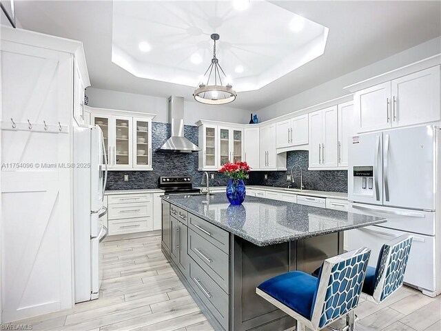 7684 County Rd 78, La Belle, FL 33935 - kitchen featuring tasteful backsplash, white appliances, a raised ceiling, and wall chimney exhaust hood