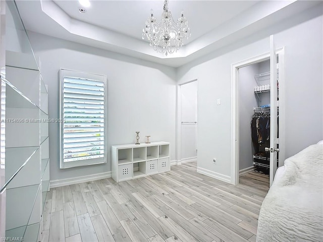 7684 County Rd 78, La Belle, FL 33935 - bedroom with a tray ceiling, light wood finished floors, a spacious closet, a chandelier, and baseboards