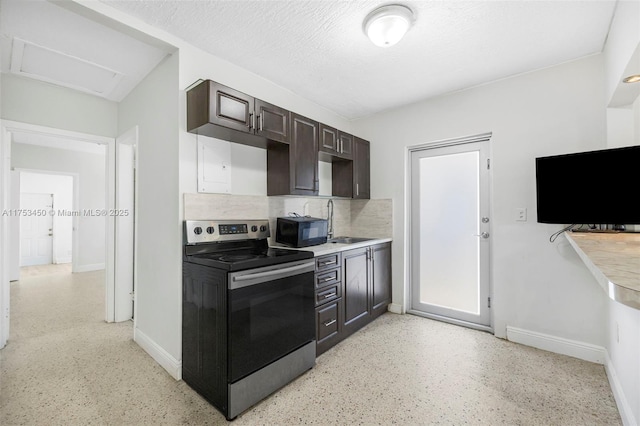 kitchen featuring black microwave, dark brown cabinetry, a sink, baseboards, and electric stove