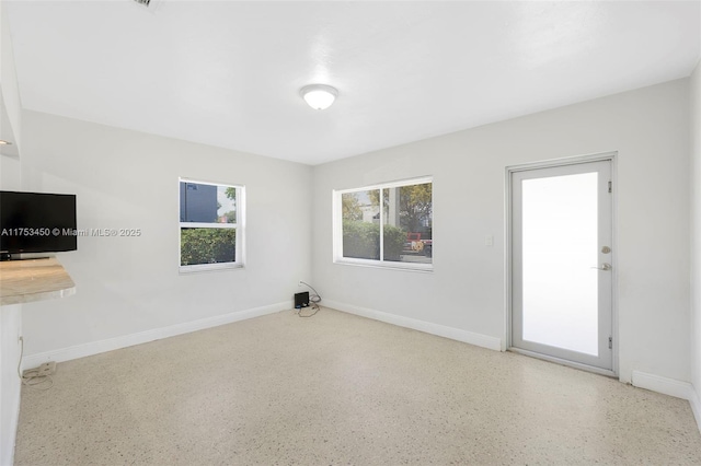 empty room featuring speckled floor and baseboards