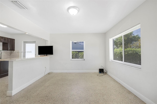 unfurnished room with a healthy amount of sunlight, baseboards, and visible vents