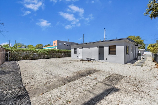 back of property with a fenced backyard, central AC, and stucco siding