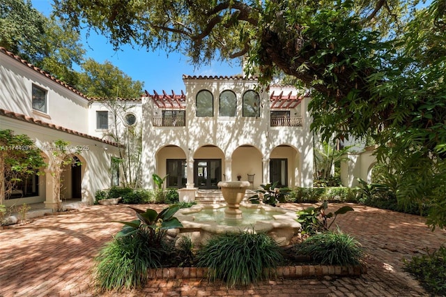 mediterranean / spanish-style house featuring a balcony, stucco siding, a tile roof, and french doors