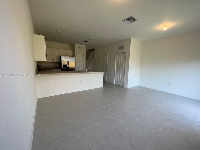 unfurnished living room featuring baseboards, visible vents, and light tile patterned flooring