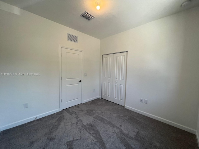 unfurnished room featuring baseboards, visible vents, and dark colored carpet