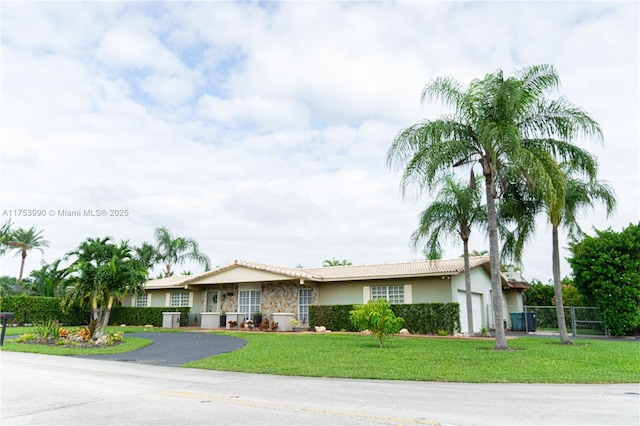 ranch-style home featuring stucco siding, fence, a garage, driveway, and a front lawn