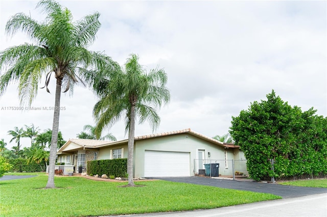 ranch-style house with aphalt driveway, an attached garage, fence, a front lawn, and stucco siding