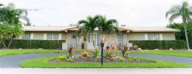 ranch-style house with a tile roof, aphalt driveway, and stucco siding