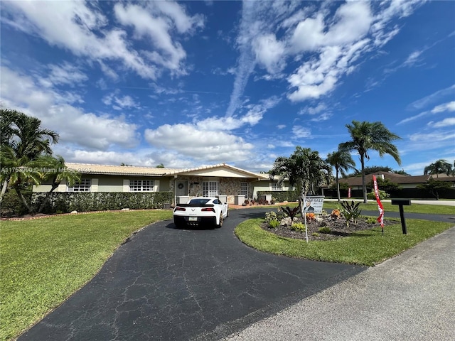 single story home featuring driveway, a front yard, a tile roof, and stucco siding