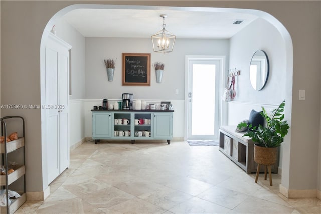 interior space with arched walkways, a chandelier, visible vents, and baseboards