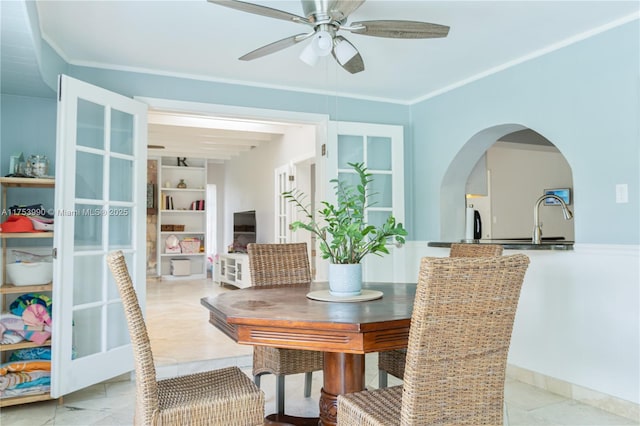 dining room with a ceiling fan, arched walkways, and crown molding