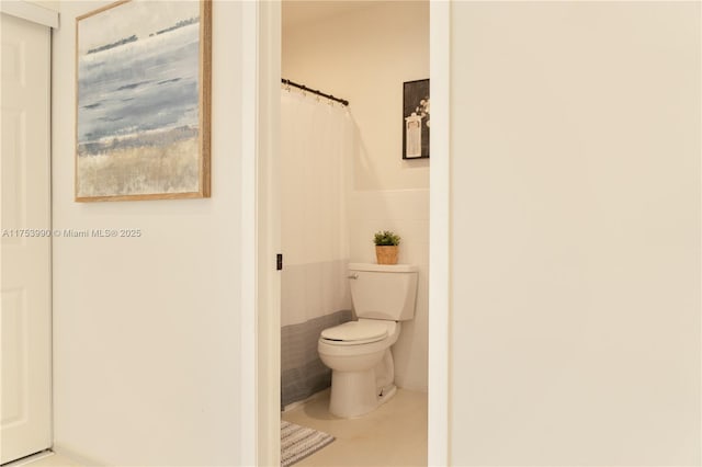 bathroom featuring tile patterned floors, toilet, and tile walls