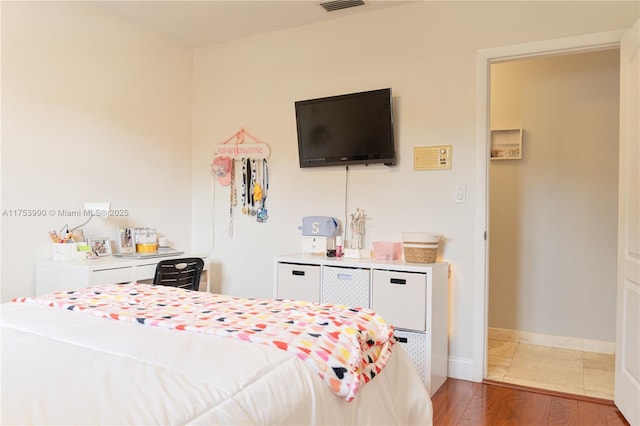 bedroom with wood finished floors, visible vents, and baseboards