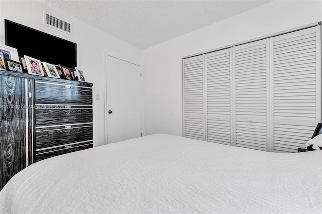 bedroom featuring a closet, visible vents, and a textured ceiling