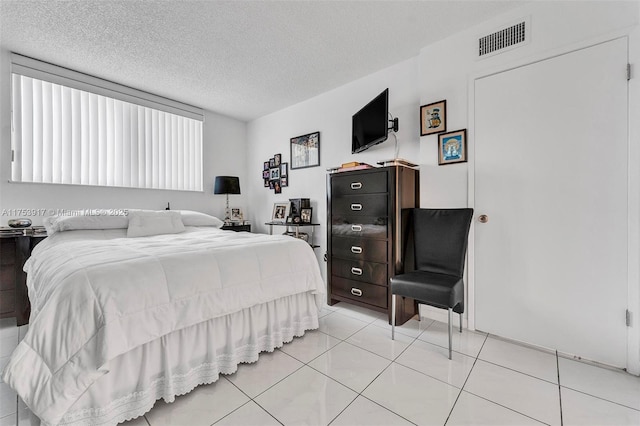 bedroom featuring visible vents, a textured ceiling, and light tile patterned floors