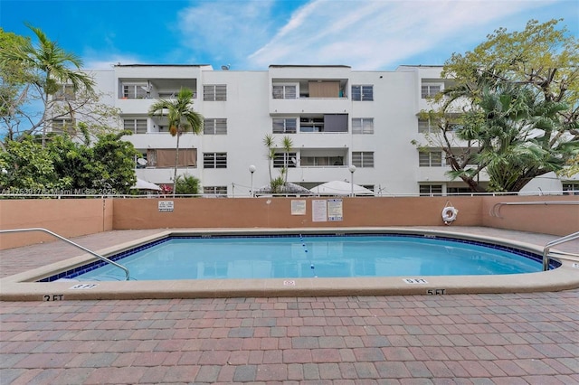 pool with a patio area and fence