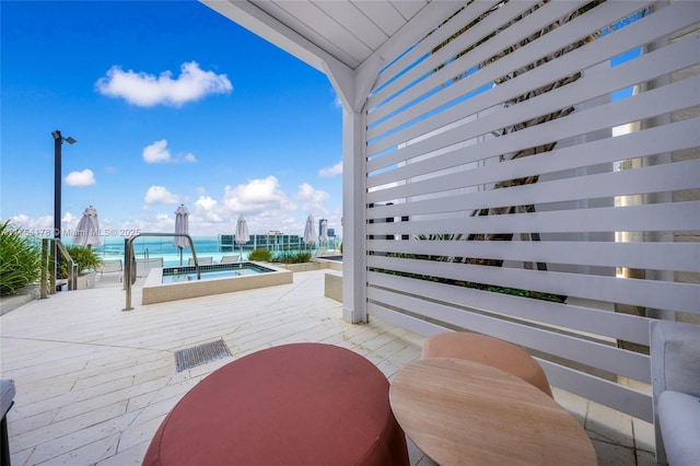 view of patio featuring outdoor dining area, a water view, a jacuzzi, and a community pool