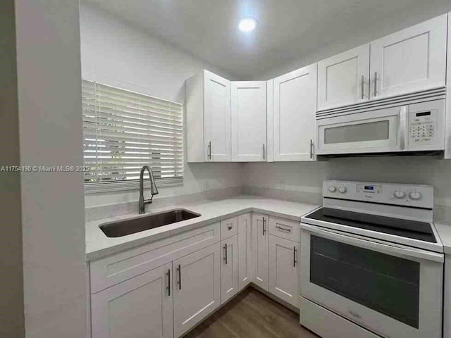 kitchen featuring white appliances, white cabinets, light countertops, and a sink