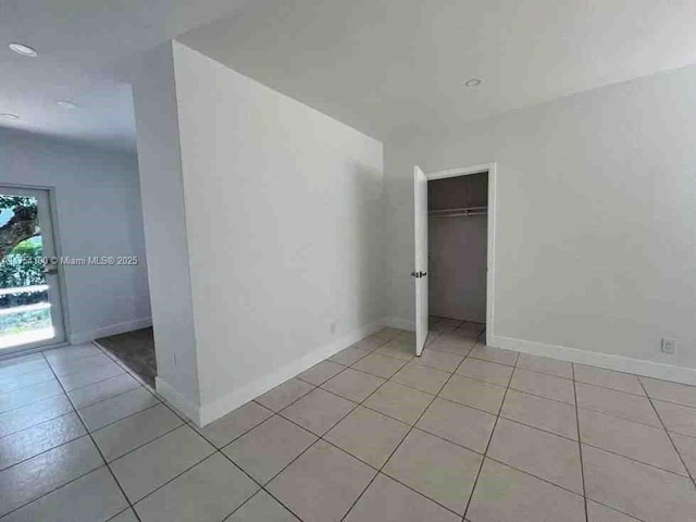 unfurnished bedroom with a closet, baseboards, and light tile patterned flooring