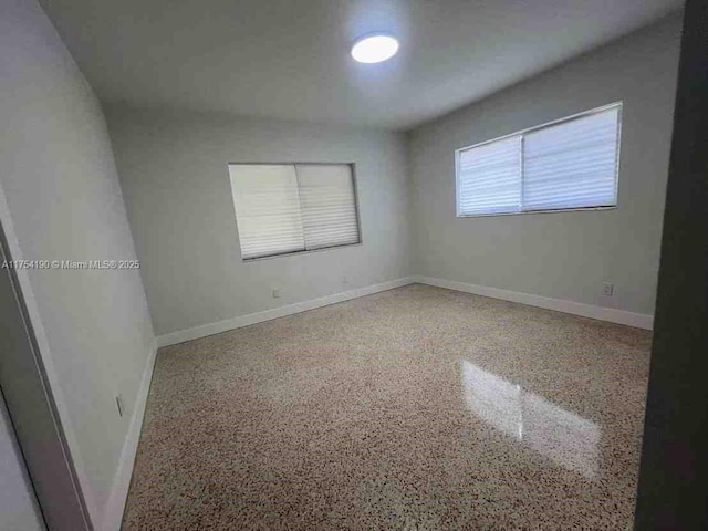 unfurnished room with speckled floor and baseboards