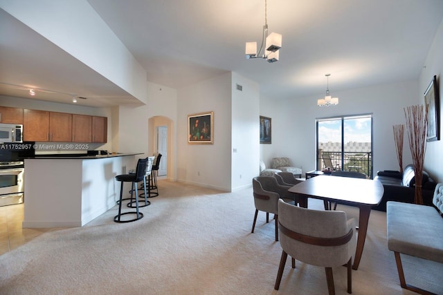 dining space featuring arched walkways, a chandelier, light colored carpet, visible vents, and baseboards