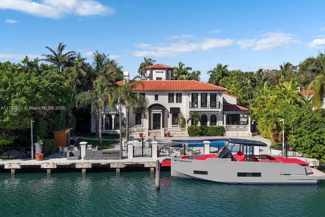 back of property featuring a patio, a water view, a balcony, and an outdoor pool