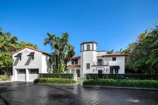 mediterranean / spanish home featuring a garage, a tiled roof, a balcony, and stucco siding