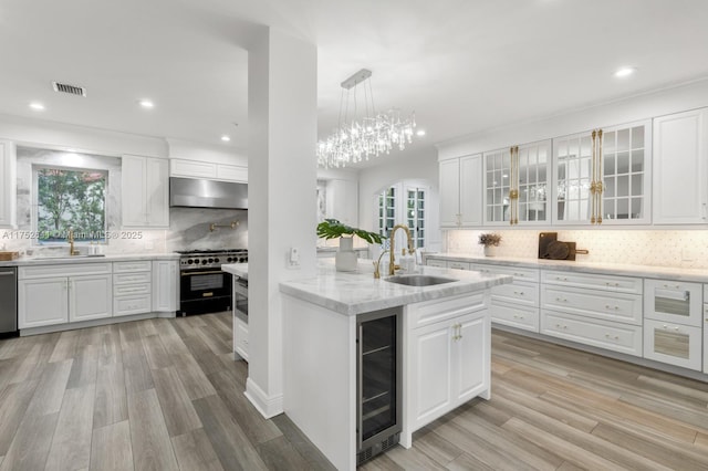 kitchen with beverage cooler, appliances with stainless steel finishes, a sink, and under cabinet range hood