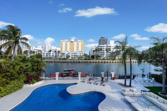 outdoor pool with a patio area, a water view, a city view, and fence