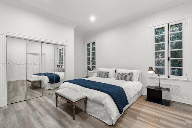 bedroom with ornamental molding, a closet, baseboards, and wood finished floors