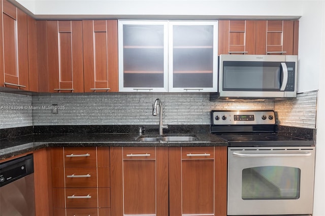 kitchen with stainless steel appliances, tasteful backsplash, brown cabinetry, a sink, and dark stone counters