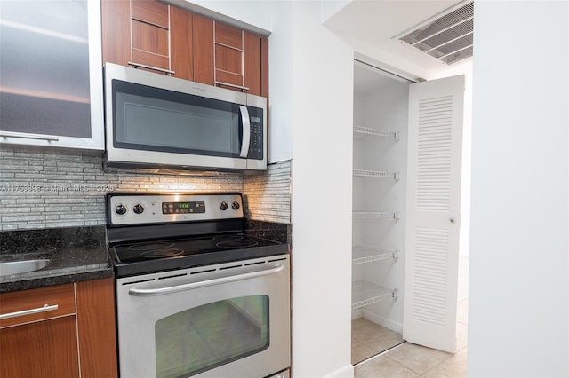 kitchen featuring stainless steel appliances, brown cabinetry, visible vents, and light tile patterned floors