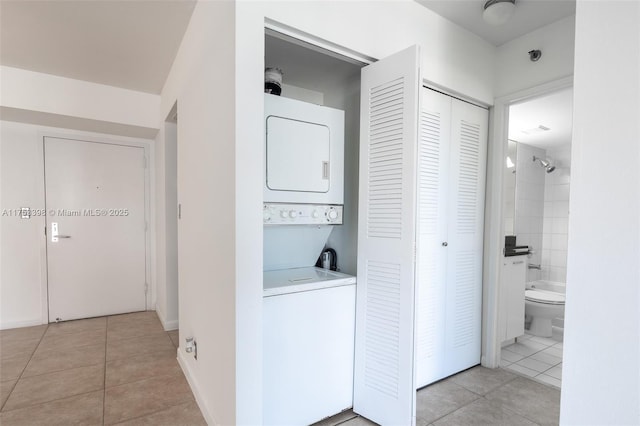 washroom with stacked washer and clothes dryer, light tile patterned floors, and laundry area