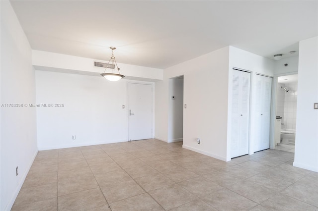 spare room featuring light tile patterned floors, visible vents, and baseboards