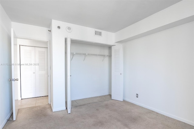 unfurnished bedroom with carpet floors, baseboards, visible vents, and a closet