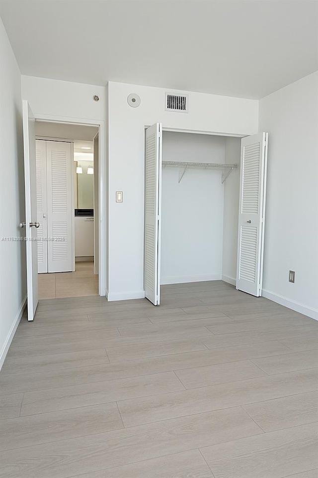 3300 NE 192nd St Unit 1908, Aventura, FL 33180 - unfurnished bedroom featuring a closet, baseboards, visible vents, and light wood-type flooring