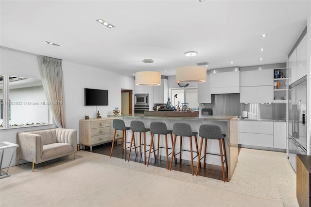 kitchen with a center island, a breakfast bar area, stainless steel appliances, white cabinets, and modern cabinets