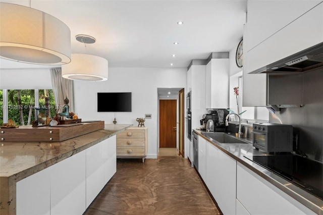 kitchen with modern cabinets, finished concrete floors, black electric cooktop, white cabinetry, and a sink