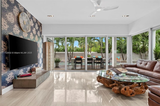 living room featuring an accent wall, ceiling fan, and wallpapered walls