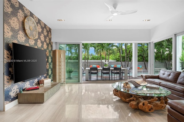 living area featuring wallpapered walls, ceiling fan, an accent wall, and visible vents