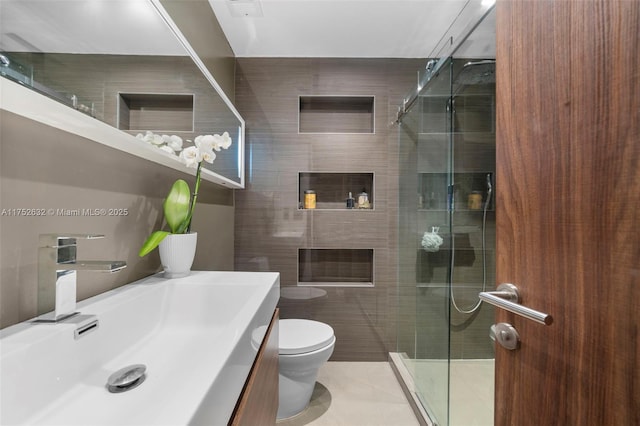 full bath with tile walls, toilet, vanity, a shower stall, and tile patterned floors