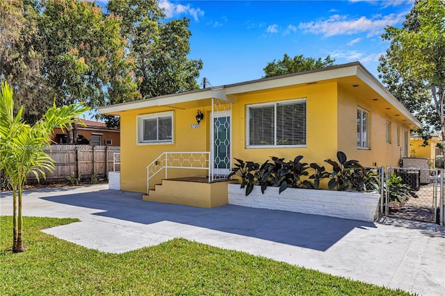 view of front facade featuring a front yard, fence, a patio, and stucco siding