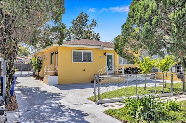 view of front facade featuring a fenced front yard, concrete driveway, roof with shingles, and stucco siding